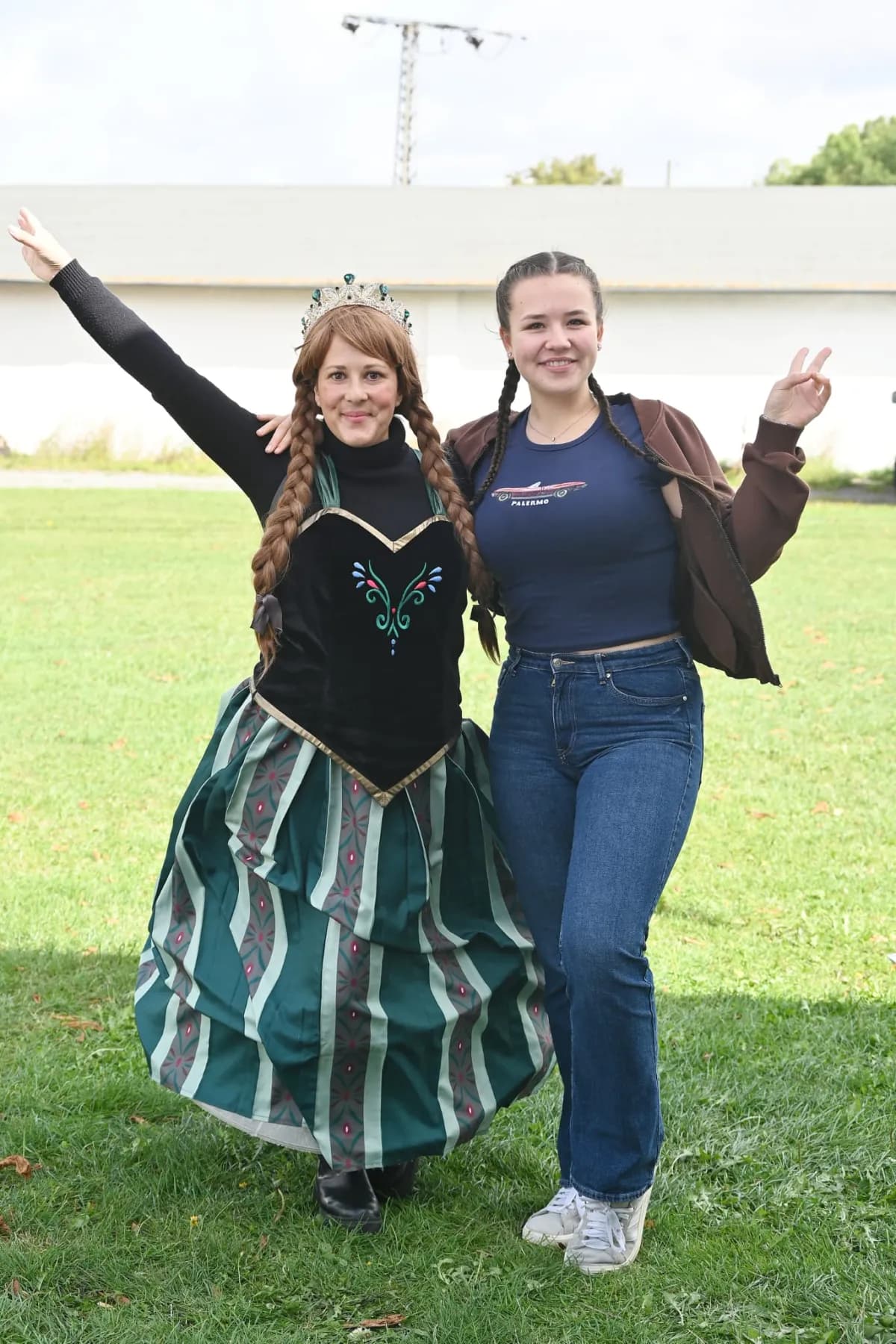 Die Eiskönigin und eine junge Frau tanzen ausgelassen auf der Wiese.