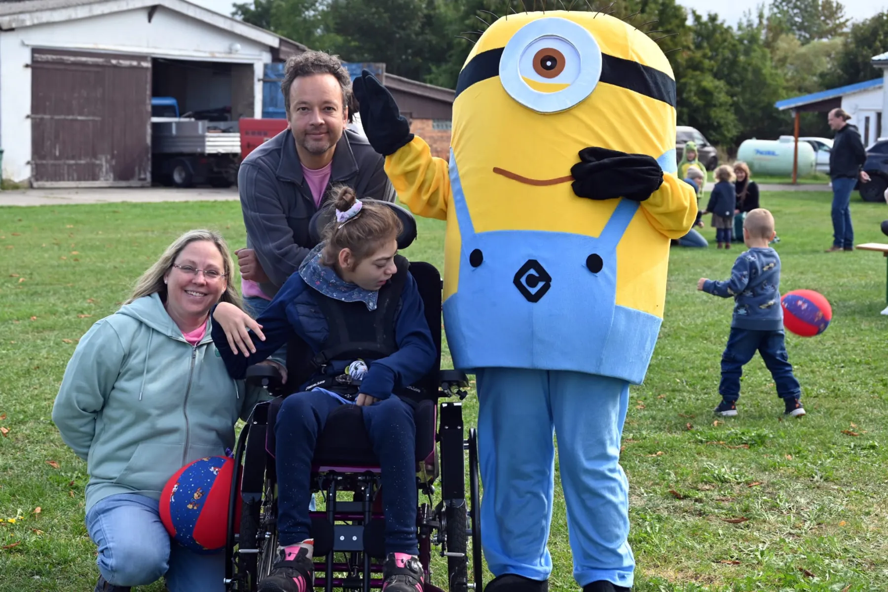 Eine Familie mit Kind im Rollstuhl macht ein Foto mit dem Minion.