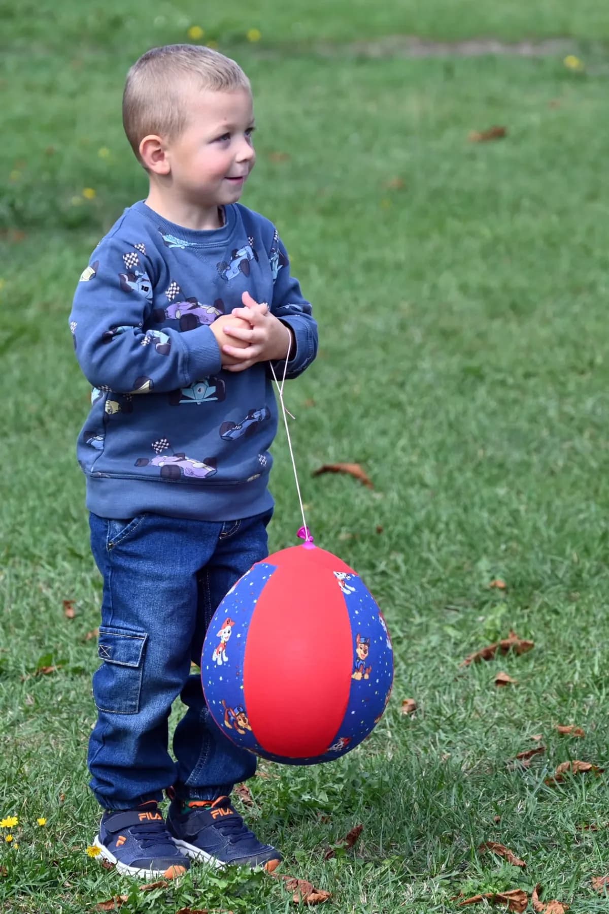 Ein kleiner Junge hält einen bunten Ball an einer Schnur.