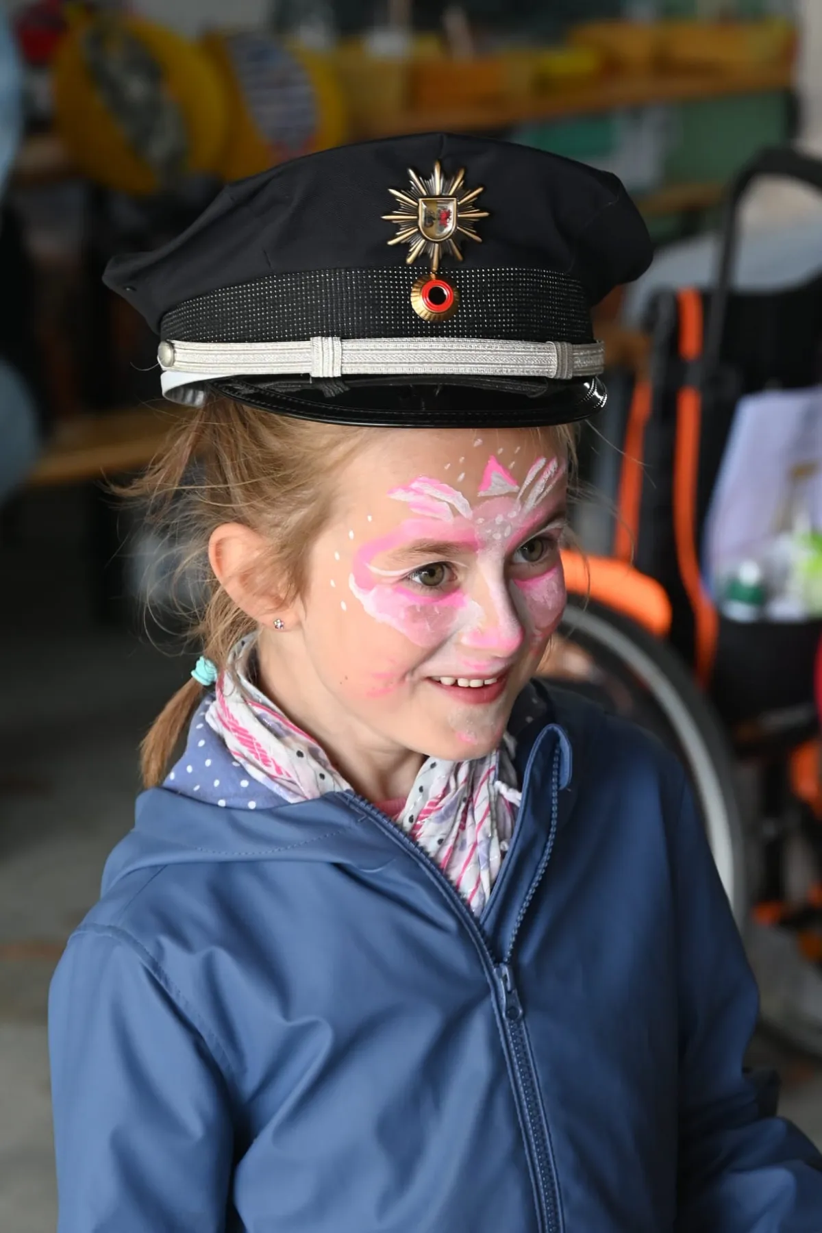Ein Mädchen mit Glitzerschminke trägt eine Polizeimütze.
