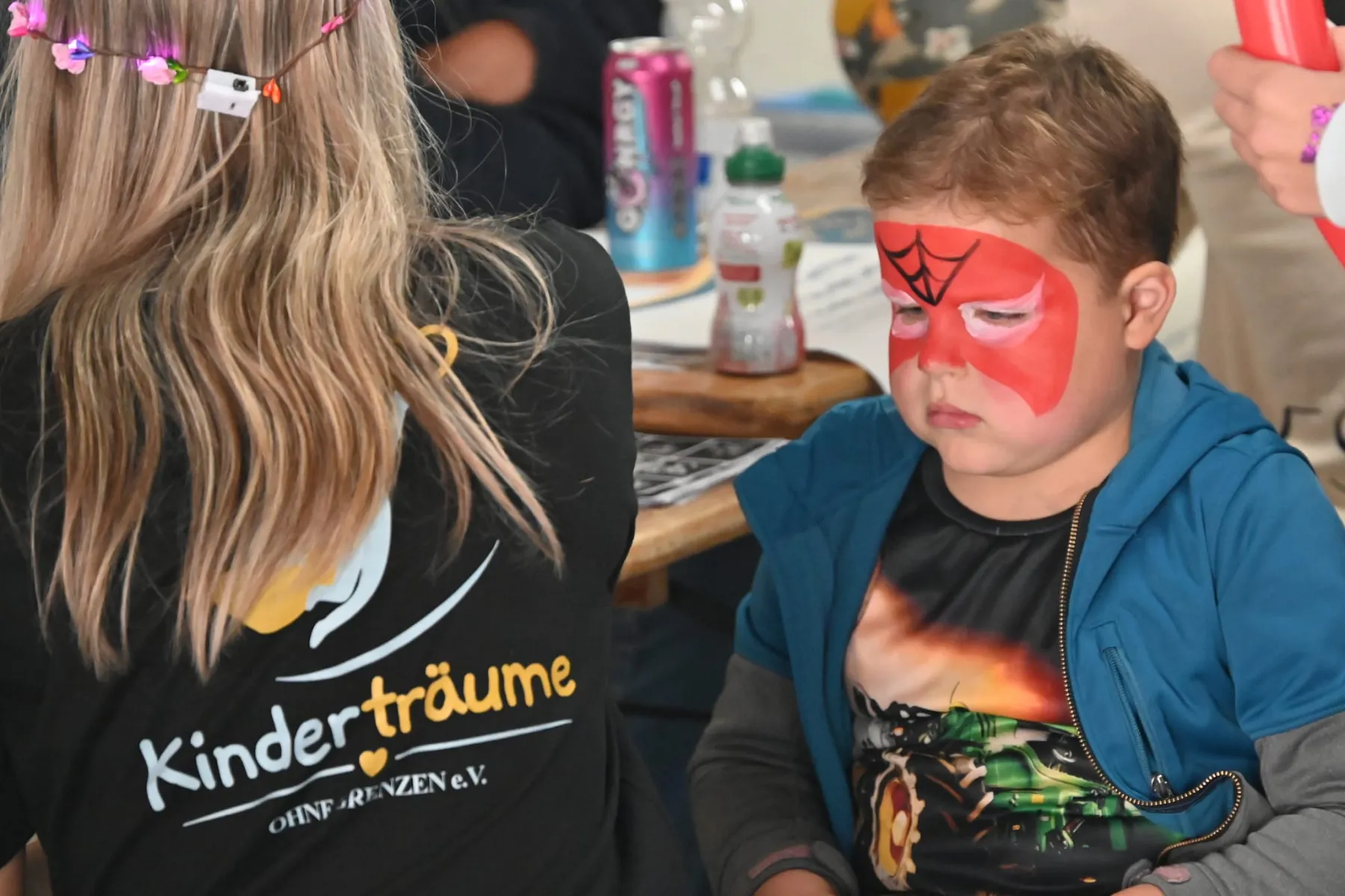 Ein Junge mit Spider-Man-Schminke sitzt am Schminktisch.