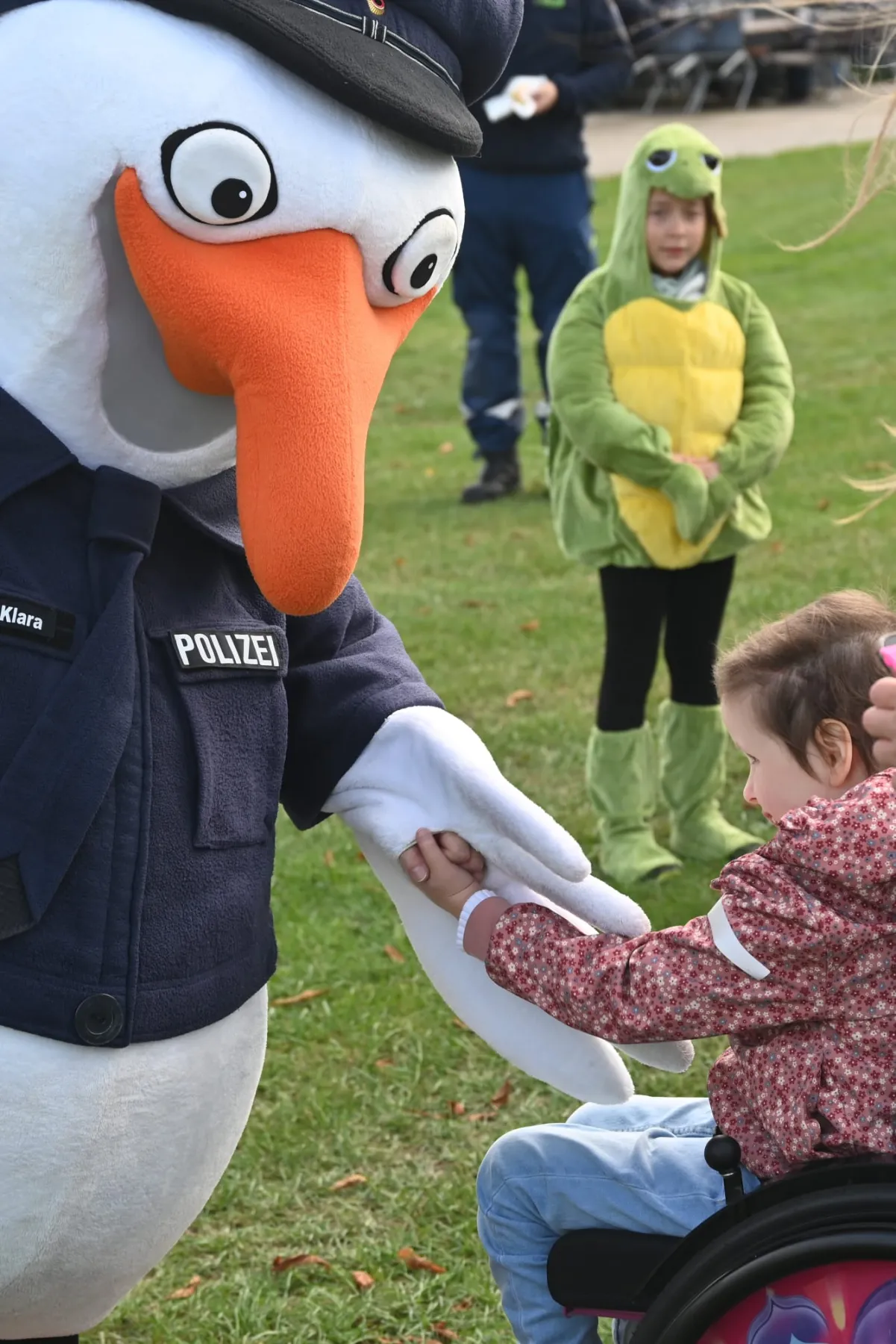 Der Polizei-Storch trifft ein Kind im Froschkostüm.